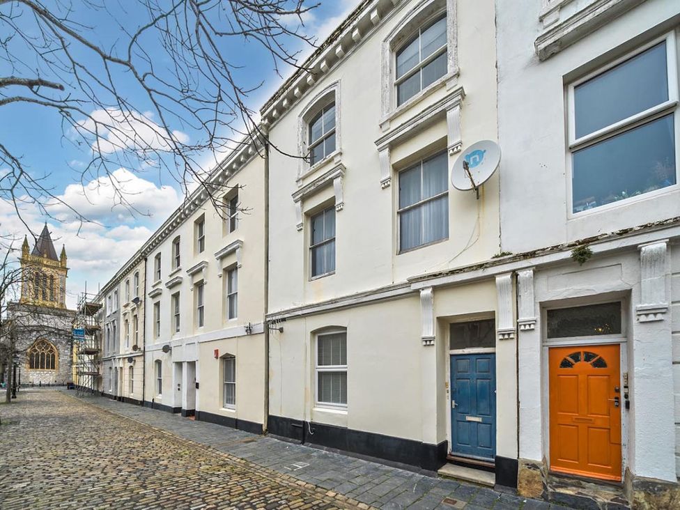 A building with multiple doors and windows on a cobbled street near a church