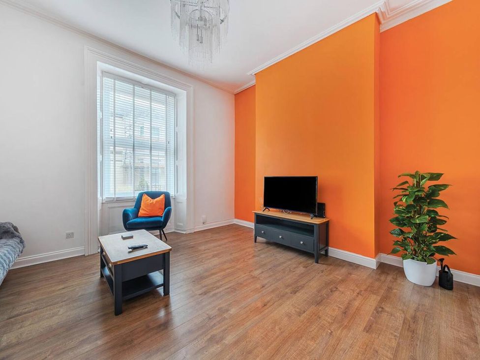 A living room with a television and an armchair at The Old Barn in Manchester