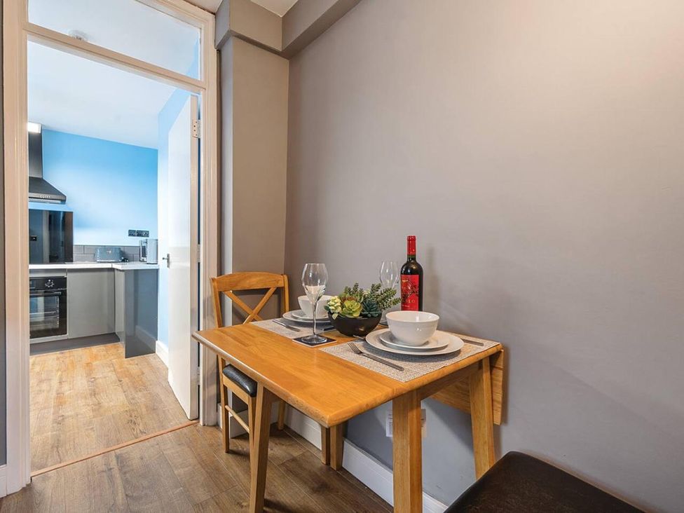 A dining area with a table and chairs showing a wine bottle and glasses at the property in 