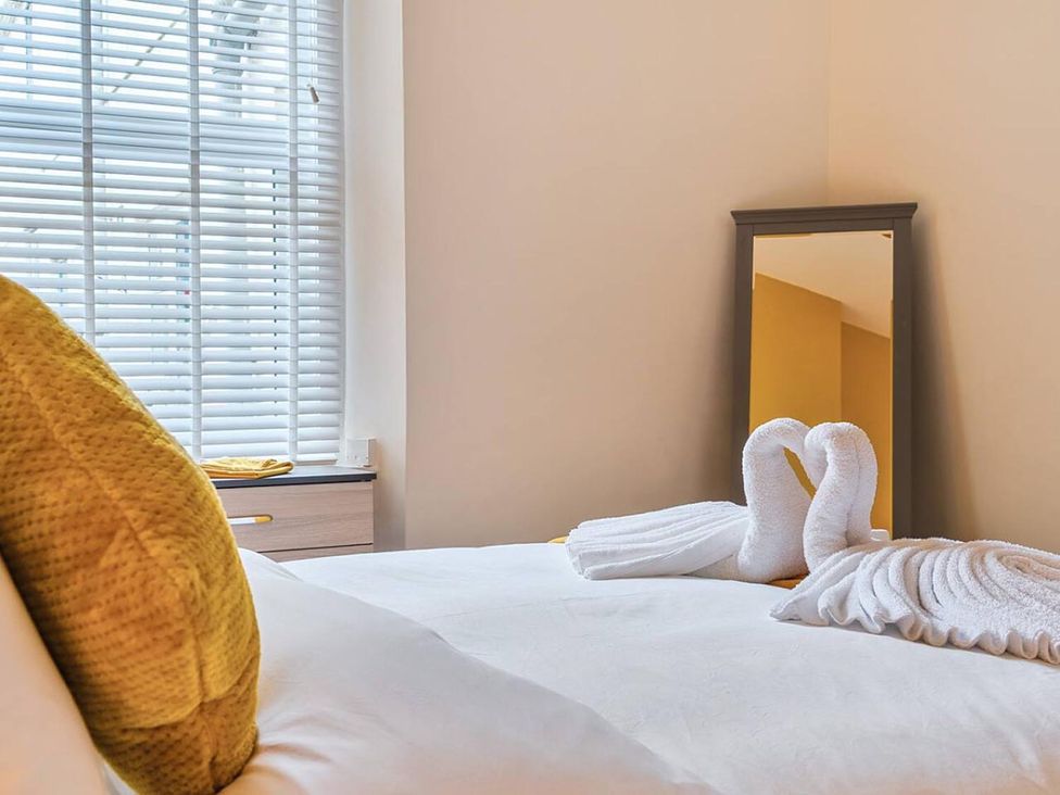 A bedroom with a bed and towels arranged on the bed at 