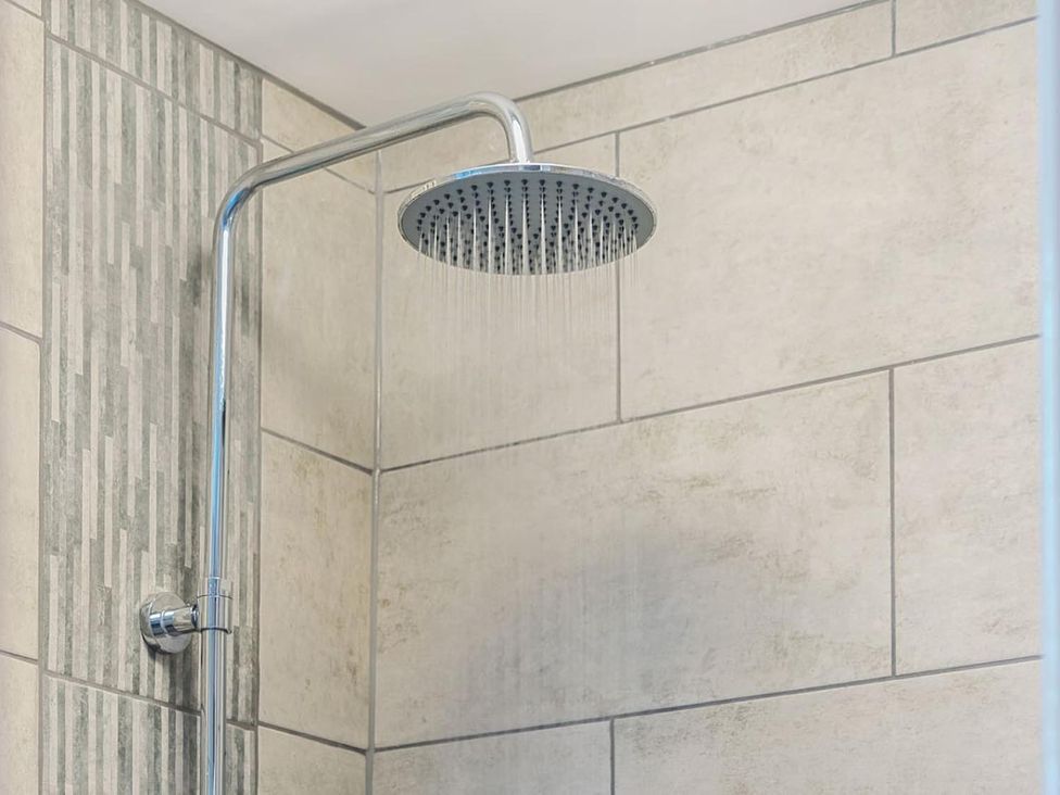 A showerhead mounted on tiled wall in a bathroom