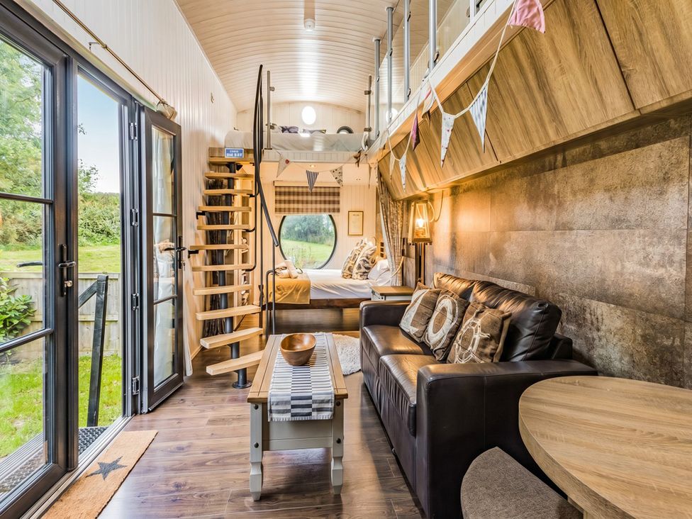 A living room with a sofa and stairs leading to a bed at the property