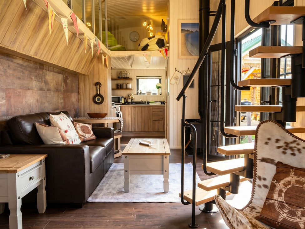 A living room with a staircase and kitchen area at a property in an unknown location