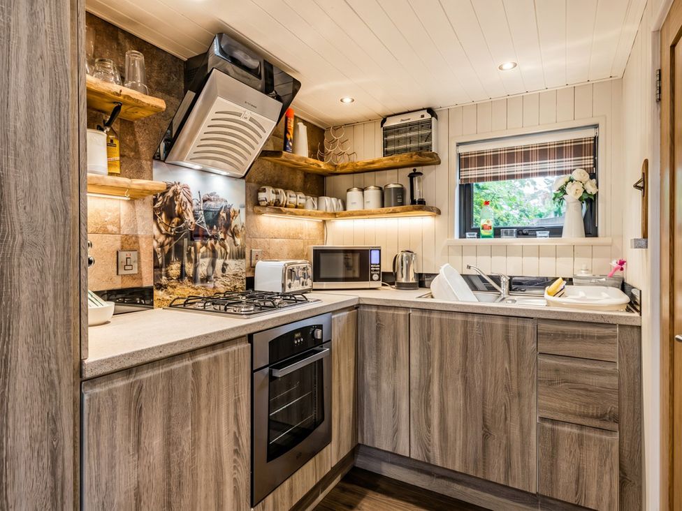 A kitchen with appliances and wooden shelves at The Old Barn in Manchester