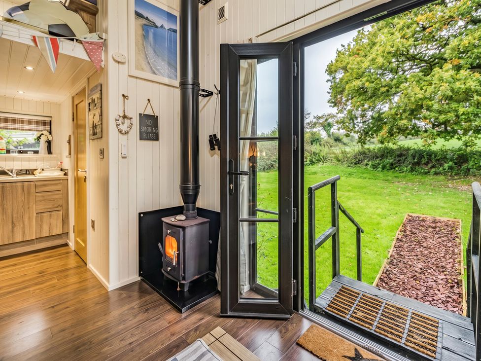 A living room with a wood stove and open door at a cabin in an outdoor setting