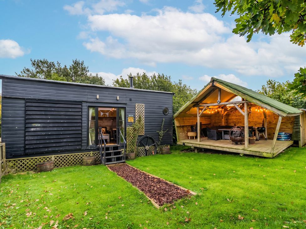 A tiny house with a wooden deck and outdoor seating in the garden