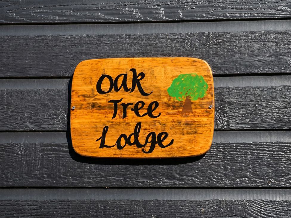 A wooden sign stating 'Oak Tree Lodge' with a tree illustration