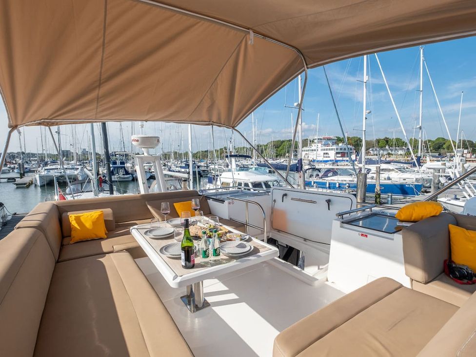 An outdoor deck area with a table set for dining on a boat at the marina