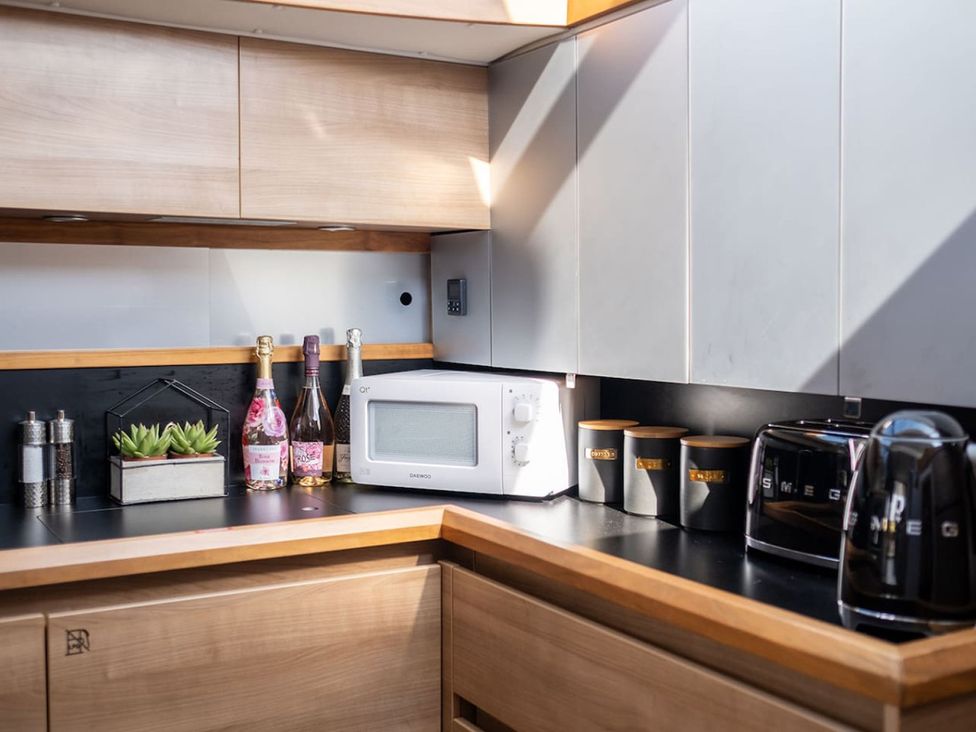 A kitchen with a microwave and bottles of champagne at The Old Barn in Manchester