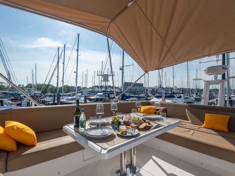 An outdoor seating area with food and drinks on a yacht at a marina