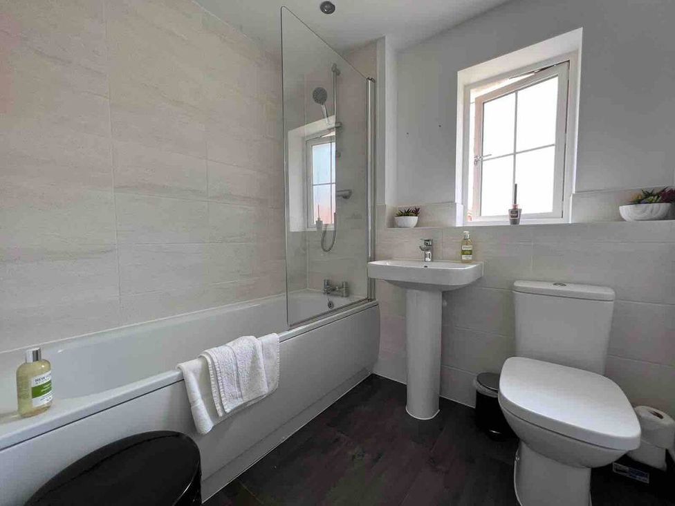 A bathroom with a bathtub, wash basin, and toilet at The Old Barn in Manchester