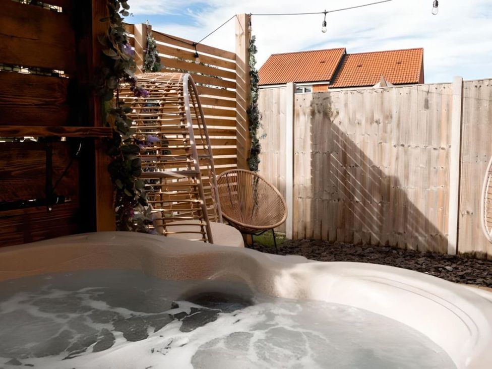 An outdoor space with a hot tub and wooden fence at The Old Barn in Manchester