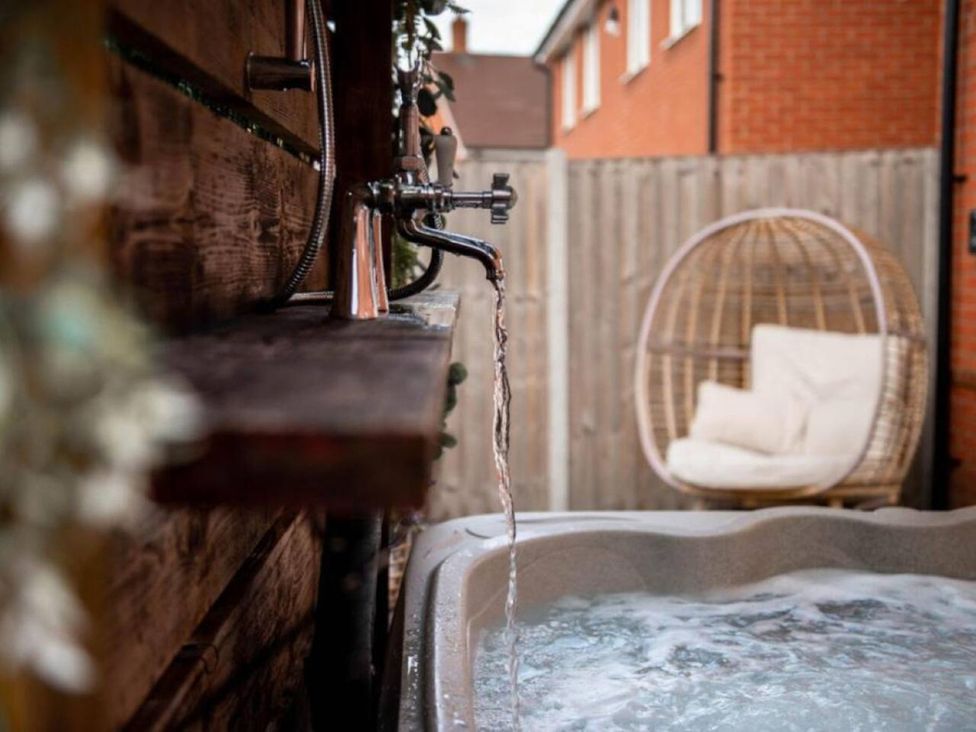 A hot tub and water tap in an outdoor area with a hanging chair