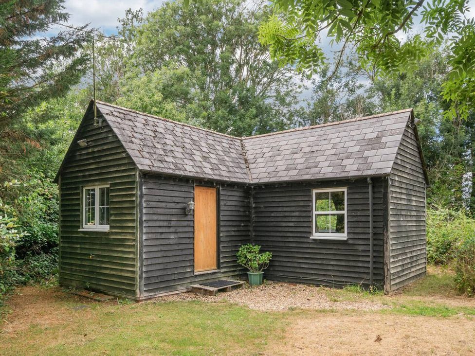 A cabin with a wooden door and windows surrounded by greenery at The Hideaway