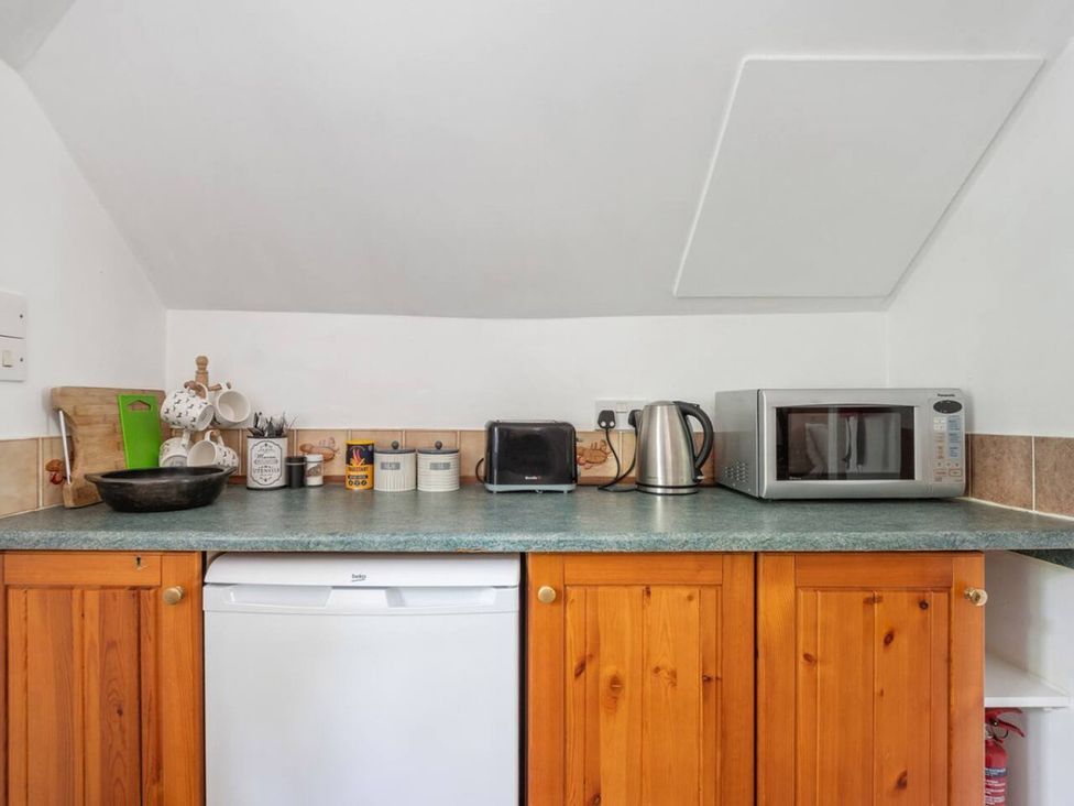 A kitchen area with a sink, microwave, kettle, and cooking utensils at The Old Post Office 