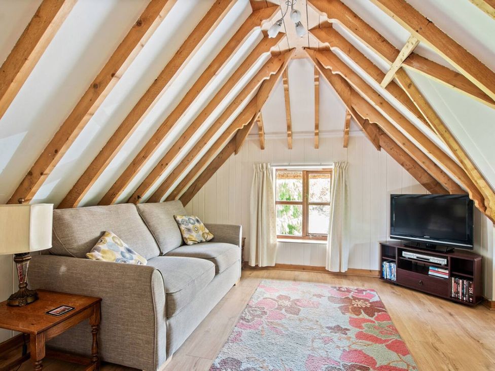 A living room with a sofa and television at Walnut Tree Cottage