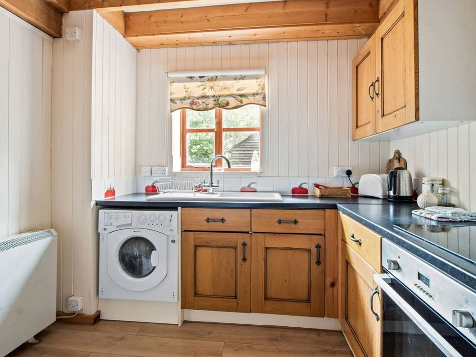 A kitchen with wooden cabinets and a washing machine at Walnut Tree Cottage