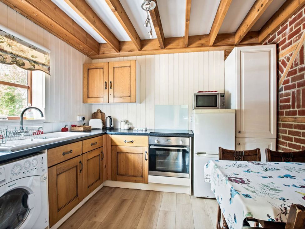 A kitchen with wooden cabinets and appliances at Walnut Tree Cottage