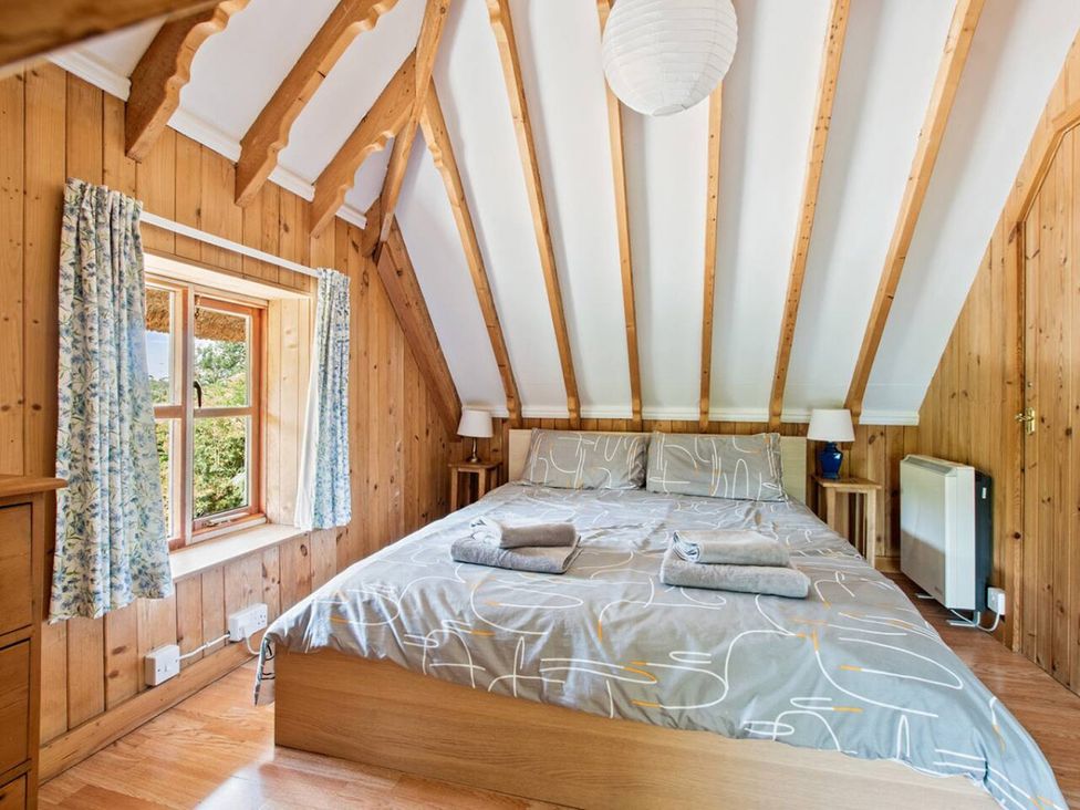 A bedroom with a bed and window at Walnut Tree Cottage