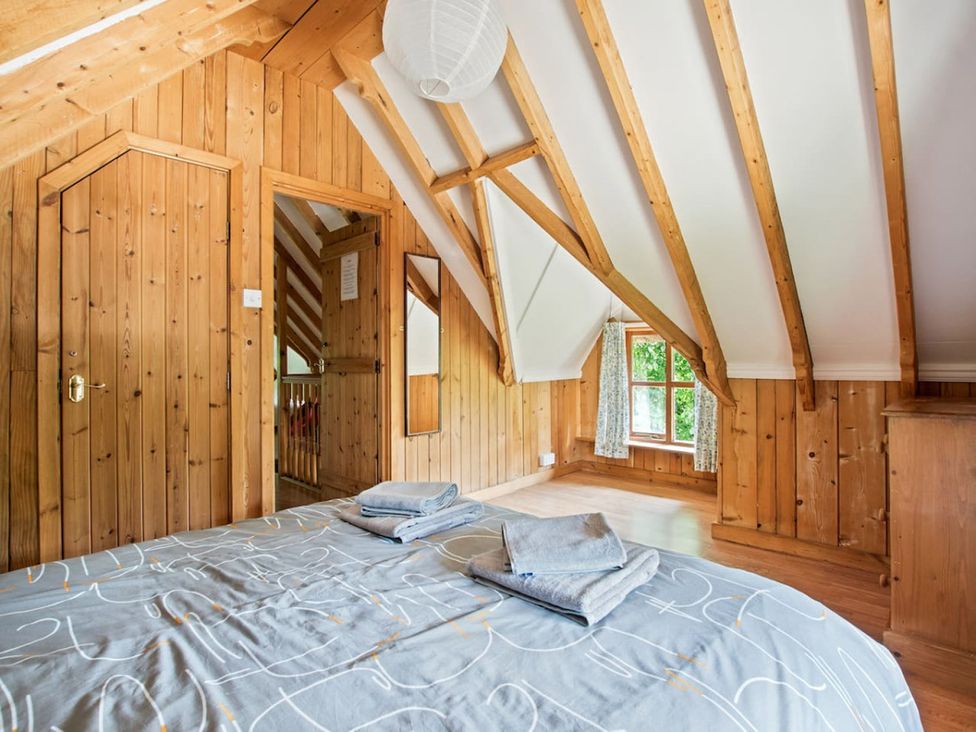 A bedroom with sloping wooden walls and a bed at Walnut Tree Cottage