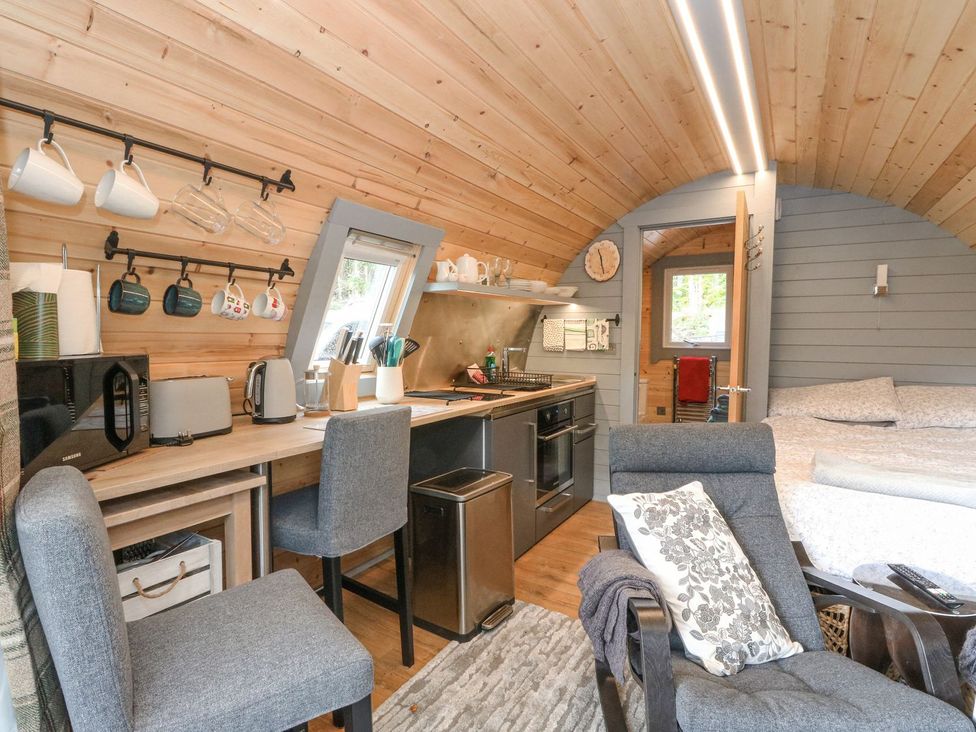 A living room and kitchen area with appliances and seating at Elleric Pods - The Last Resort Appin