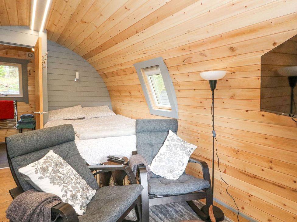 A bedroom with a bed and two armchairs at Elleric Pods - The Last Resort in Appin