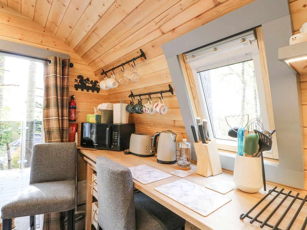 A kitchen with bar stools and various kitchen appliances at Elleric Pods - The Last Resort, Appin