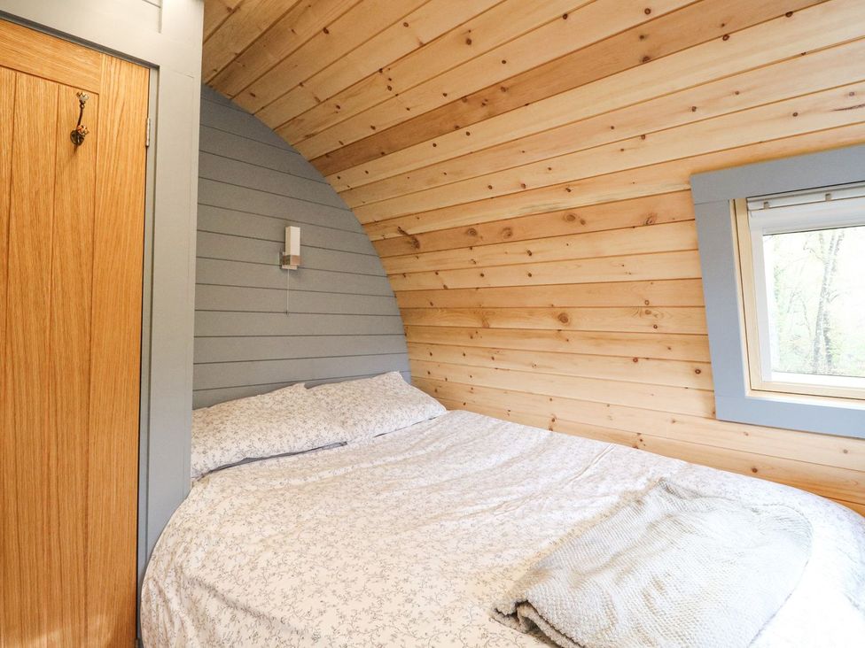 A bedroom with a bed and wooden furnishings at Elleric Pods - The Last Resort in Appin