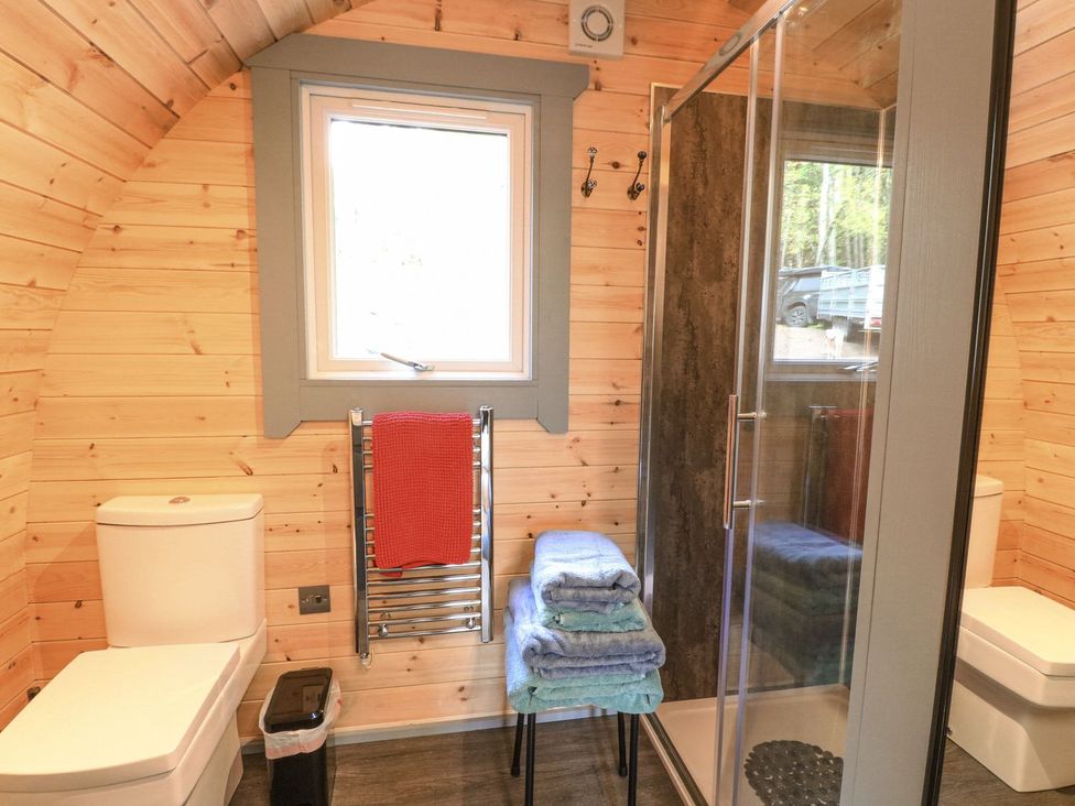 A bathroom with a shower, toilet, and towel rack at Elleric Pods - The Last Resort in Appin