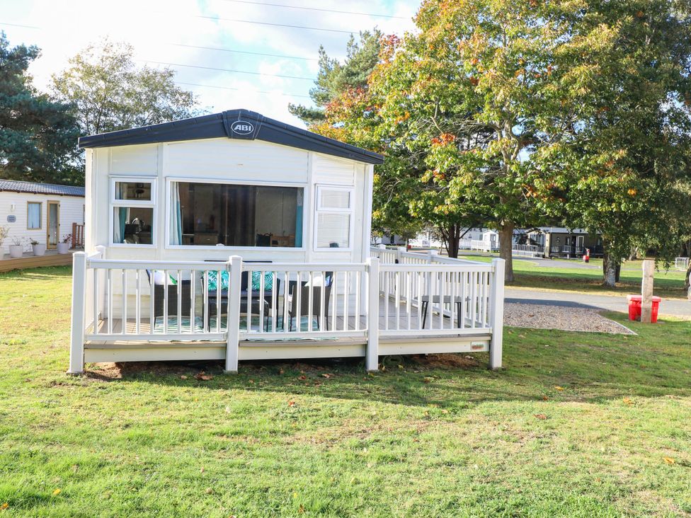 A mobile home with a deck in a grassy area at Four Seasons Great Yarmouth
