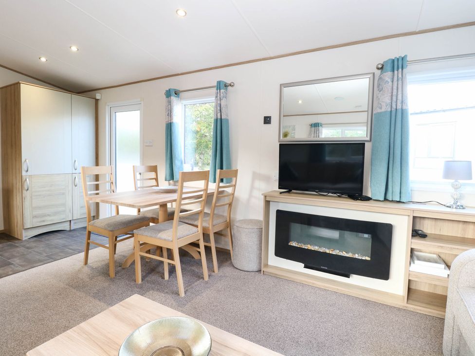 A living room with a dining table and television at Four Seasons in Great Yarmouth