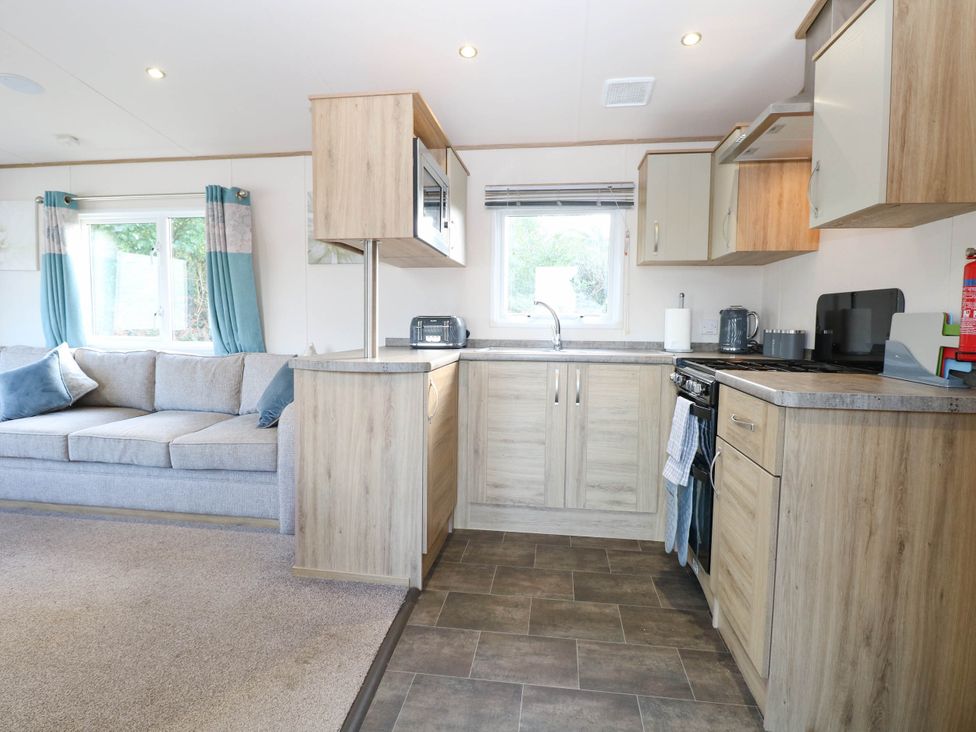 A kitchen with cabinets and a sofa at Four Seasons in Great Yarmouth