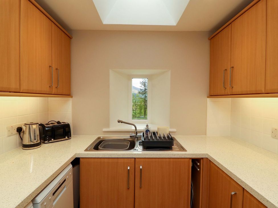 A kitchen with wooden cabinets and sink at Swallow's Nest in Keswick