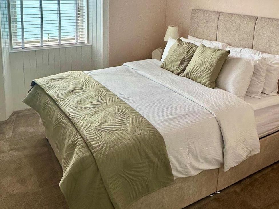 A bedroom featuring a bed with pillows and a bedside lamp