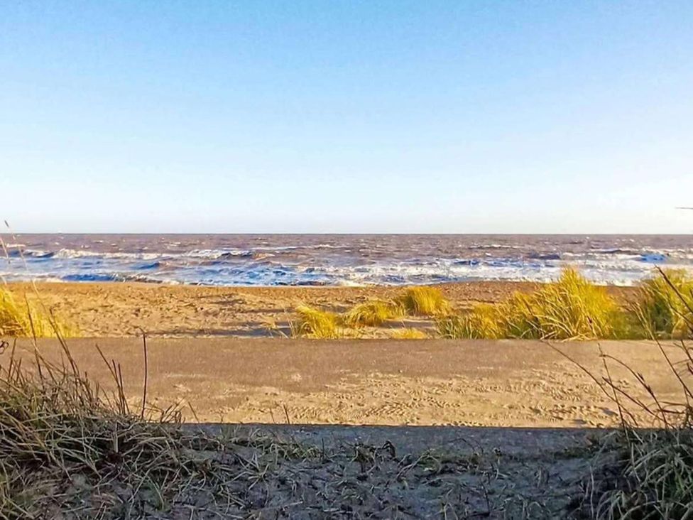 A view of the ocean with sand and grass at Snowdrop Lodge Dog friendly Nr Anderby Creek Alford