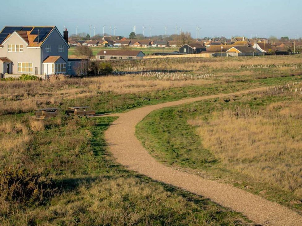 A house and path in a field with wind turbines in the background at Snowdrop Lodge Dog friendly Nr Anderby Creek Alford