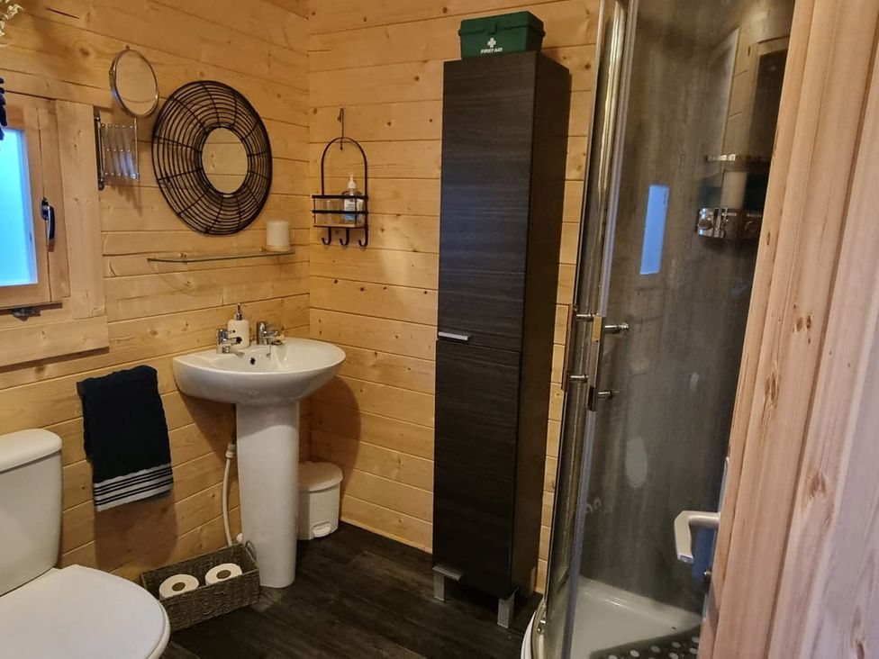 A bathroom with a shower, sink, toilet and storage cabinet at 2 bed Lodge near Dunoon on the Shore Front, Innellan near Dunoon