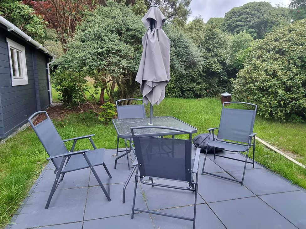 A garden with a table and chairs under an umbrella at 2 bed Lodge near Dunoon in Innellan near Dunoon