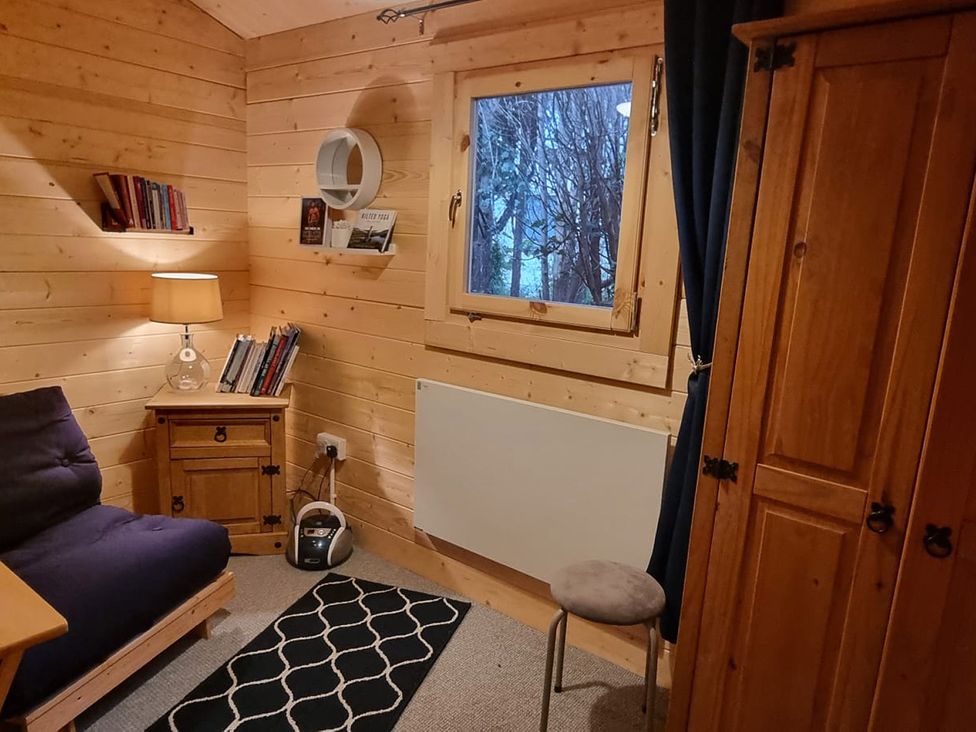 A room with a sofa, lamp, bookshelf, and window at 2 bed Lodge near Dunoon on the Shore Front Innellan near Dunoon