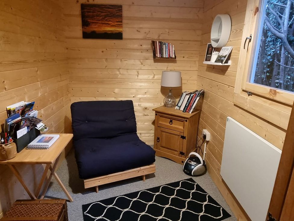 A study with a chair, side table, and bookshelf at 2 bed Lodge near Dunoon on the Shore Front, Innellan near Dunoon