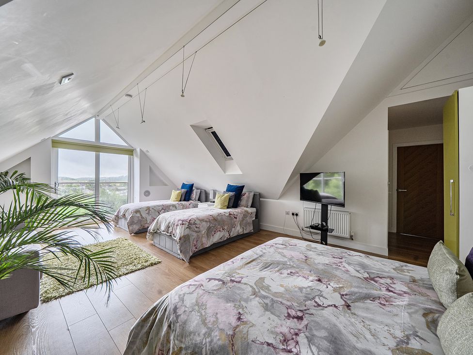 A bedroom with two beds and a television at 5 Bed House, Sleeps 14 with Hot Tub and Bar, Tavistock