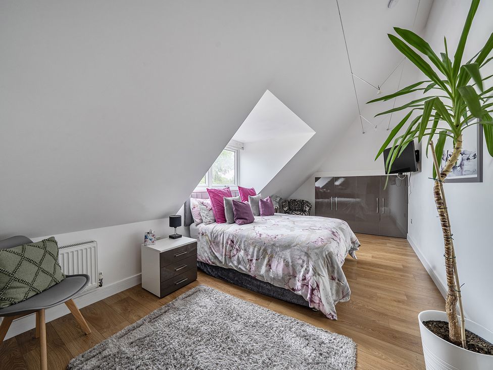 A bedroom with a bed and a plant at 5 Bed House, Sleeps 14 with Hot Tub and Bar in Tavistock