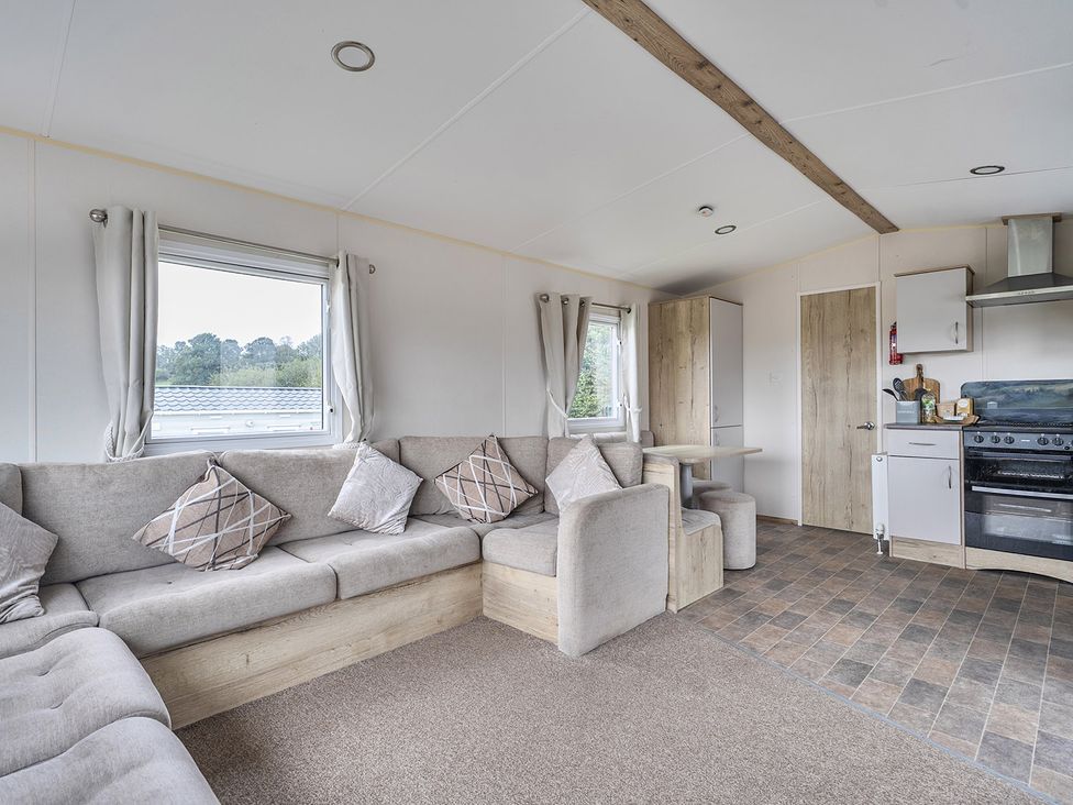 A living room with a sofa and kitchen unit at Ty dee seaview escapes in Looe