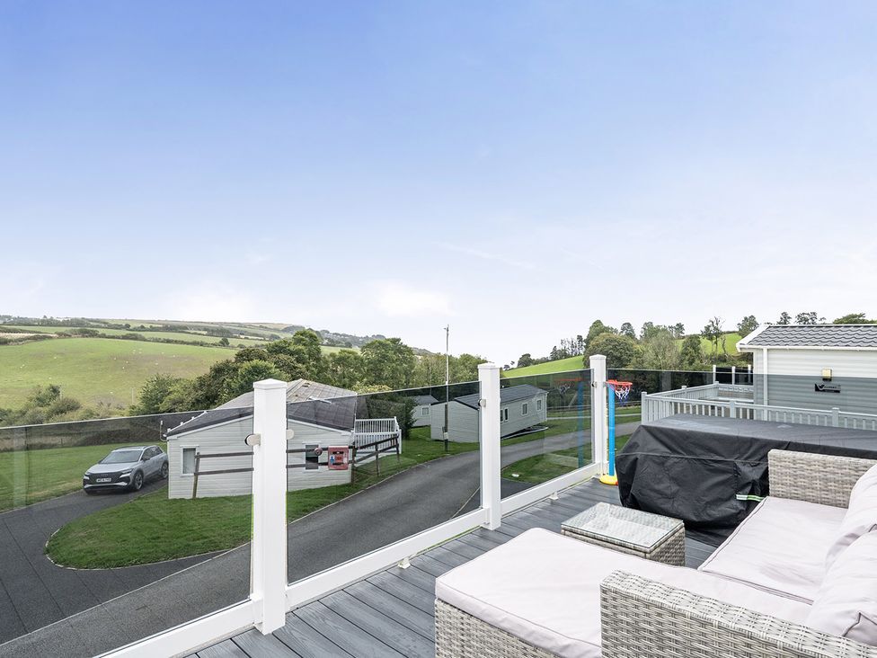 A sitting area with glass railing overlooking hills at Ty dee seaview escapes in Looe