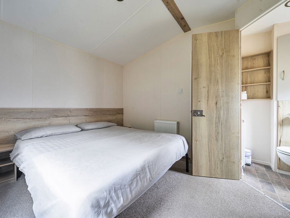 A bedroom with a bed and a bathroom door at Ty dee seaview escapes in Looe