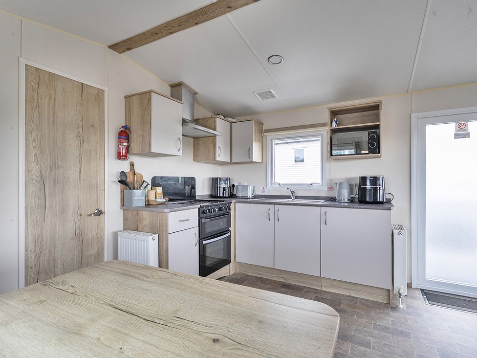 A kitchen with appliances and dining table at Ty dee seaview escapes in Looe