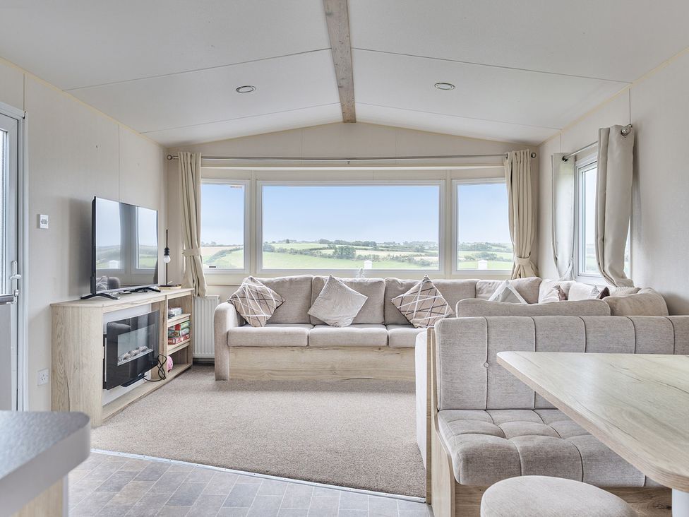 A living room with a sofa and television at Ty dee seaview escapes in Looe