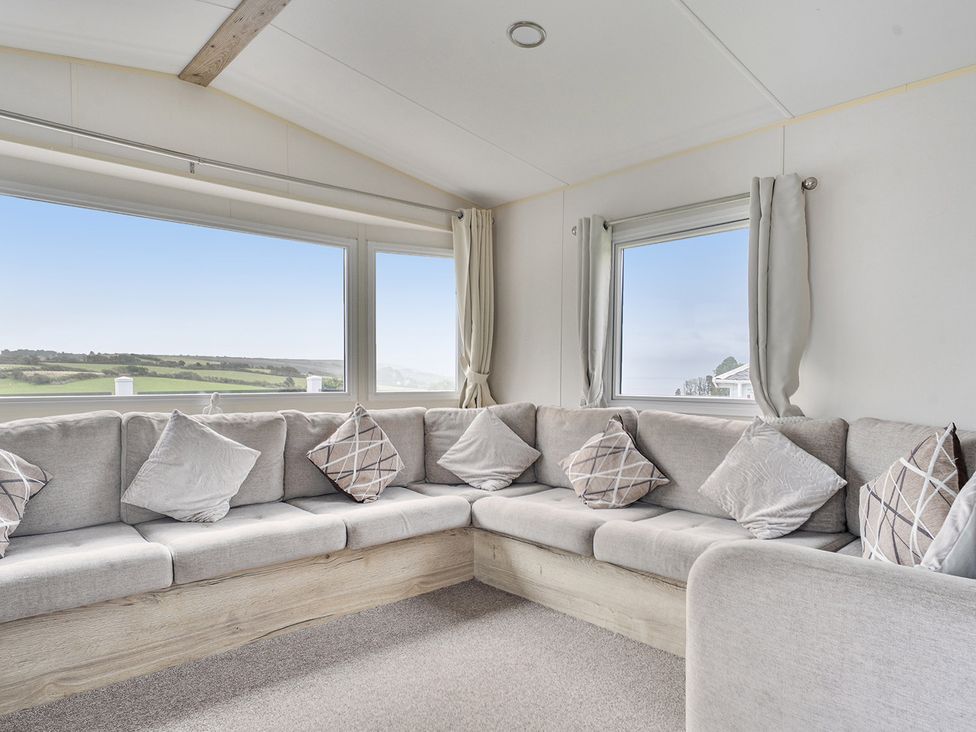 A living room with a sofa and windows at Ty dee seaview escapes in Looe