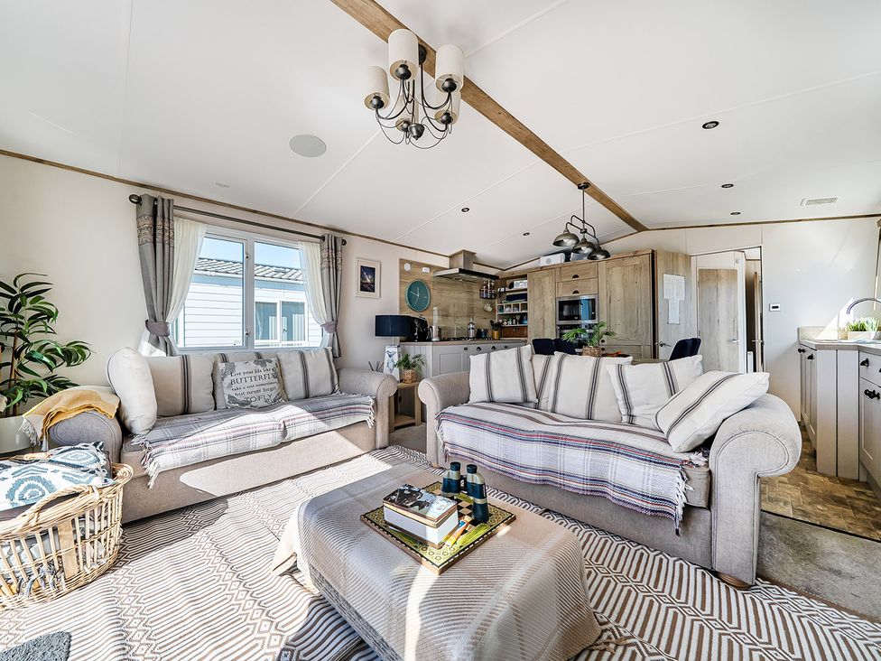 A living room featuring a sofa, coffee table, and kitchen unit at 2 Bed Caravan, Sleeps 4 with Sea Views in West Lulworth