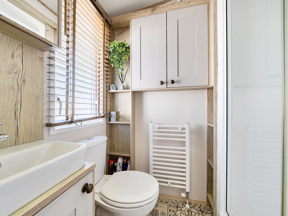 A bathroom with a toilet, sink, and shelves at 2 Bed Caravan, Sleeps 4 with Sea Views West Lulworth